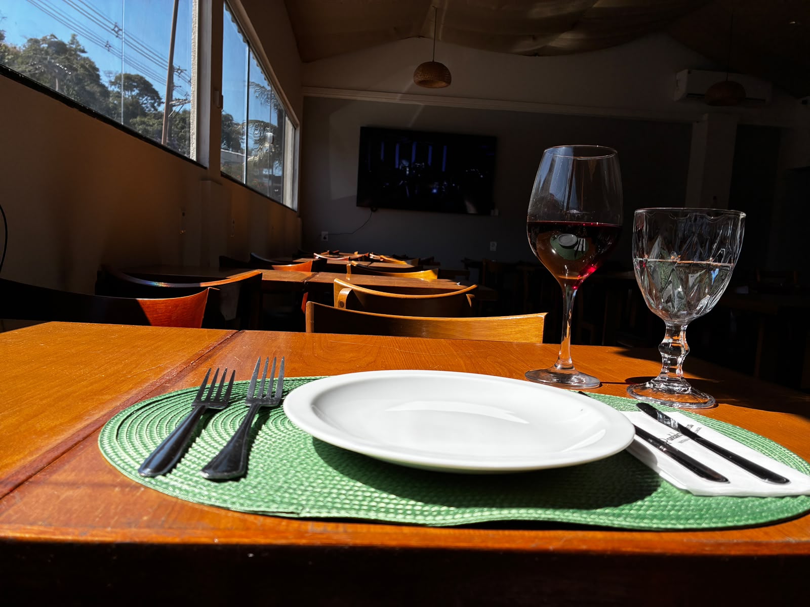 Mesa posta com taça de vinho, prato e sousplat verde